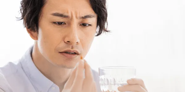 薬を怪しむ男性