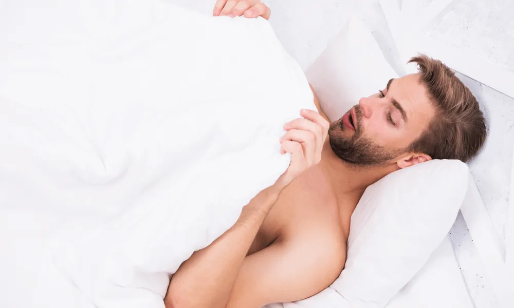 朝起きて朝勃ちを確認する男性